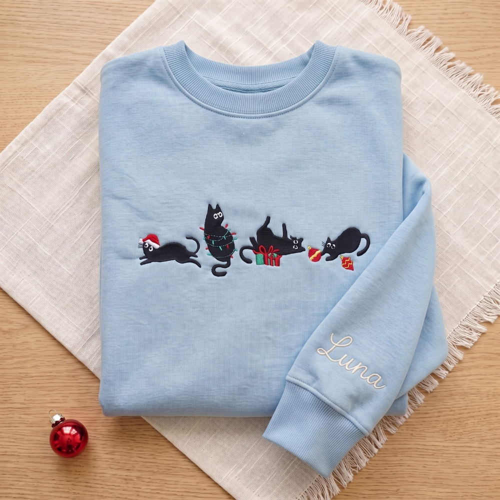 The Personalized Black Cats Christmas Mischief Santa Hat Tangled Lights Ornaments embroidered sweatshirt — front view