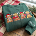 Personalized Christmas Highland Cow Santa Hat Scarf Candy Cane Bell Four Cows embroidered sweatshirt — front view