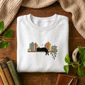 Black Cat Sleeping on Bookshelf Houseplant Coffee Cup embroidered sweatshirt — front view