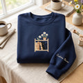 Personalized Black Cat Bookshelf Daisy Flowers Custom Name embroidered sweatshirt — front view