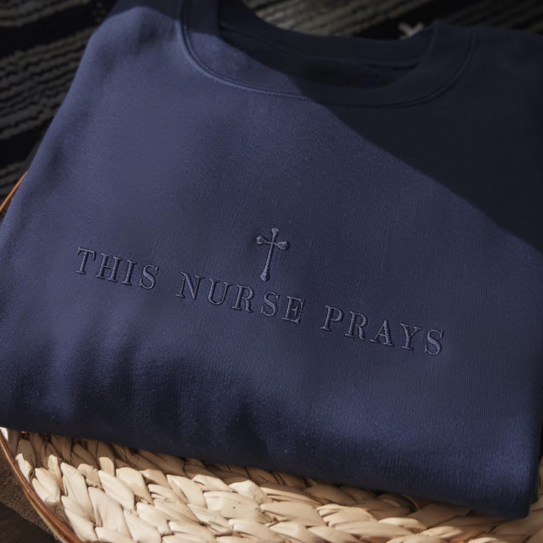 This Nurse Prays Cross Faith Christian embroidered sweatshirt — front view