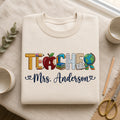 Personalized Teacher Mrs Name Alphabet School Supplies Apple Globe Books embroidered sweatshirt — front view