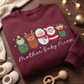 Christmas Mother Baby Nurse Swaddled Babies Holiday Characters embroidered sweatshirt — front view