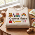 Personalized Preschool Kindergarten Abc Blocks Teddy Bear Rainbow Crayon Apple Ruler Scissors Custom Name embroidered sweatshirt — front view
