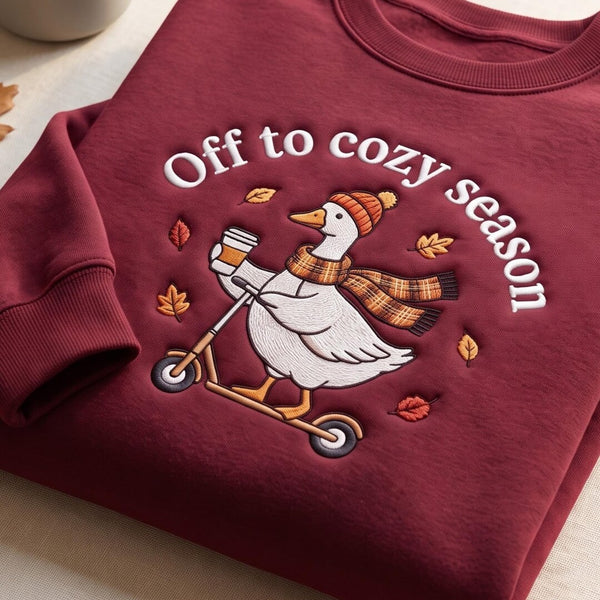 Off to Cozy Season Goose Riding Scooter Beanie Scarf Fall Leaves Coffee embroidered sweatshirt — front view