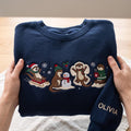 Personalized Christmas Otter Sledding Snowman Snow Angel Hot Cocoa Custom Name Sleeve embroidered sweatshirt - front view