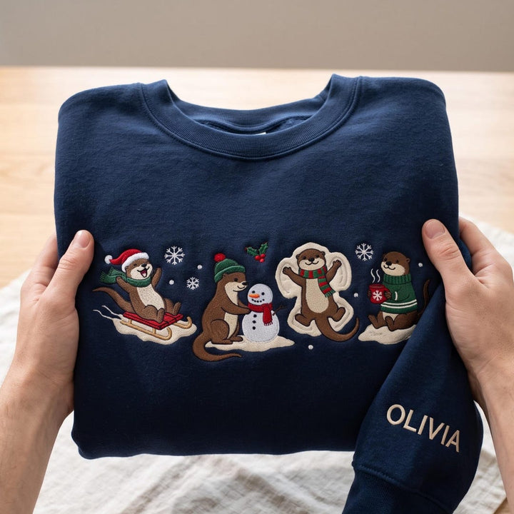 Personalized Christmas Otter Sledding Snowman Snow Angel Hot Cocoa Custom Name Sleeve embroidered sweatshirt - front view